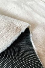 Close-up of the soft fluffy texture of a beige shaggy rug