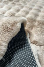 Close-up of the soft, thick pile of a brown shaggy rug