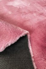 Close-up of the soft, thick pile of a pink shaggy rug